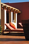 Sun lounger on a covered terrace in front of a painted wall