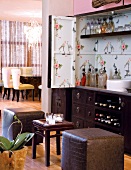 View of dining area beyond vintage-style drinks cabinet with upholstered cube stools
