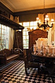A manorial room with antique furniture, a wooden Hollywood swing and a collection of white vases on the dining table
