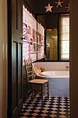Badezimmerecke mit Spiegelwand, Pastellblauen Fliesen und einem schwarz-weissen Fliesenboden im Schachbrettmuster; in der Ecke ein goldener Totenschädel