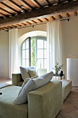 Cushions on chaise longue in front of arched terrace door in renovated country house