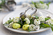 A rabbit-shaped biscuit cutter on a plate with catkins, sugar eggs and spiraea