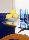 Lemons on a plate next to colored water glasses on a table
