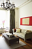Gepolsterter Couchtisch vor antikem Sofa in klassisch modernem Wohnzimmer