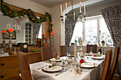 Country house dining room with Christmas garland on wall and festively set table