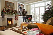 Festively decorated living room in English country house; woman holding cat in background
