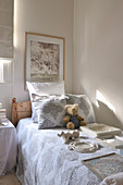 Various picture frames and teddy bear on bedspread of wooden bed