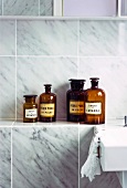 Collection of vintage bottles on shelf in bathroom with marble wall tiles