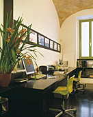 Small architect's studio in stylish Roman loft with brick vaulting; lime green chairs combined with classic black table top and floor