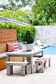 Rustic table and benches in front of pool in modern courtyard