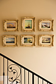 Gilt-framed pictures of ships on painted wall in stairwell