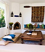 Moroccan-Greek elements in a living room with a masonry fireplace and upholstered seating