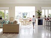 Young boy running through an open living room with a sunny dining area