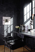 Desk below sunny window in corner of room with postmodern decor and anthracite walls