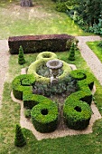 Gartengestaltung im Stil eines Schlossparks mit antiker Amphore inmitten kunstvoll geschnittener Buchsbaumhecken