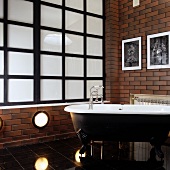 Badezimmer im Vintagestil mit freistehender Badewanne vor Wand mit Ziegellook