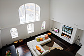 Two-storey interior of London apartment with view from above of arched window and sofa in front of gas fire