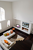 Two-storey interior of London apartment with view from above of arched window and sofa in front of gas fire