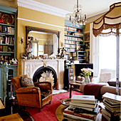 Art Nouveau salon with vintage leather armchair next to fireplace and bookcases against yellow-painted wall