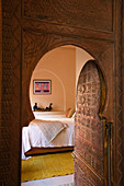 Offene Zimmertür mit Spitzbogen in marokkanischem Stil und Blick ins Schlafzimmer