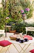 Breakfast on a bistro table with white metal chairs and plant pots on the terrace