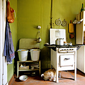 50er Jahre Vintage-Herd in schlichter Küche mit olivgrünen Wänden und Holzbank mit Wassereimern