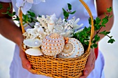 Woman holding basket containing seashells and wedding rings