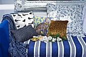 Blue and white striped couch with colourful, patterned scatter cushions in front of Baroque wall-mounted mirrors