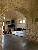 View though stone arched doorway into living room in a Trullo house