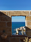 Window-like opening in stone wall with coastal view