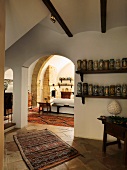 Collection of ceramic vases on shelves next to arched doorway with view into Mediterranean living room