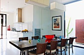Esstisch mit Stühlen aus dunklem Holz in offenem Wohnraum und Blick in Küche