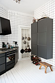 Designer Küche in Schwarz-weiss - Schwarze Schränke an raumhoch gefliester Wand und weisser Dielenboden