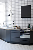 Kitchen counter with black base cabinets against walls tiled from floor to ceiling