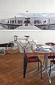 Bauhaus-style table and chair in front of large photo on wall above bicycle