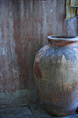 Simple ceramic vessel on floor against weathered house facade