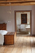 Chest at foot of bed and view into simple bathroom through open doorway