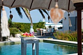 Sunny day beside the pool with refreshing fruit platter on stool