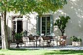 Terrassenplatz mit langem Tisch und Stühlen vor dem Haus unter Akazienbaum