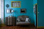 Bedroom in original combination of colours and fabrics - grey striped chest of drawers and matching antique sofa against walls painted blue and green