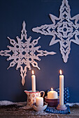 Lit candles on floor and Christmas decorations on wall