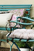 Cushions in various patterns on turquoise bench and garden chair in vintage French country house style