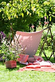 Cushions and picnic blanket in garden beneath awning made from length of fabric
