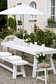 Wicker baskets and porcelain crockery on white picnic table in garden