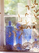 Blue glass vases behind a transparent tulle curtain with floral embroidery