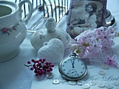 Pocket watch in front of hyacinth bloom, porcelain vessels and antique photograph