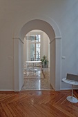 Classic arched doorway in foyer and view of round table in dining room with terrazzo floor