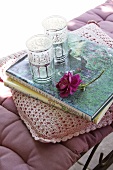 Seat cushions, scatter cushion with crocheted cover, books, glasses and a rose