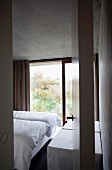 View through revolving interior door into purist bedroom in concrete house
