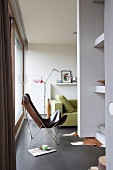 Lederner Fledermaussessel und lindgrünes Sofa mit Tolomeo-Stehlampe in modernem Wohnraum mit poliertem Betonboden